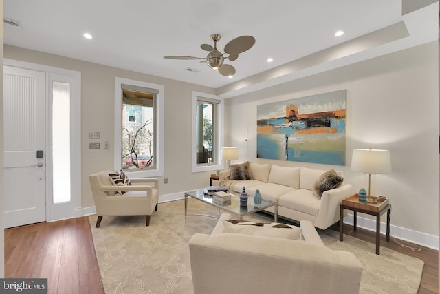 living room with light wood-style flooring, visible vents, and baseboards