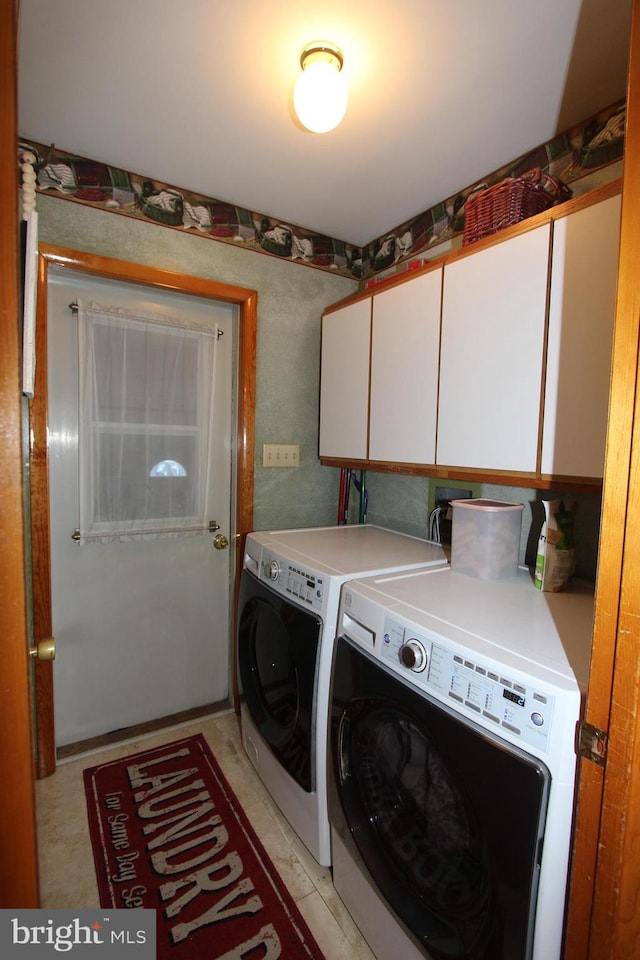 clothes washing area featuring washing machine and clothes dryer and cabinet space