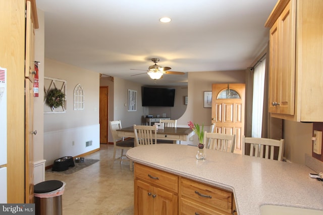 kitchen with a peninsula, ceiling fan, visible vents, and light countertops