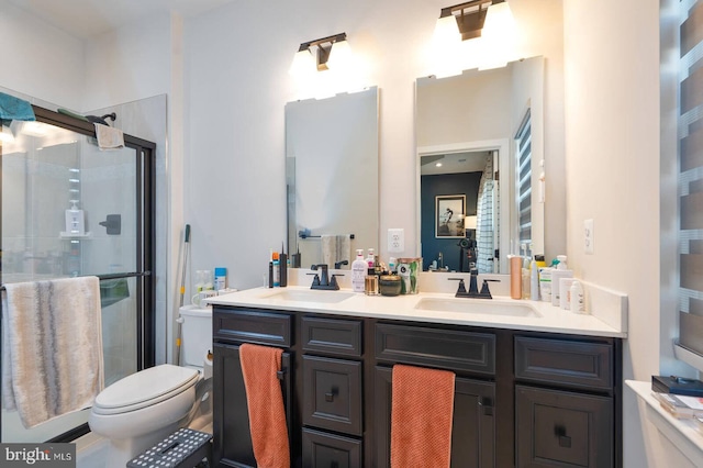 bathroom with double vanity, a sink, toilet, and a shower stall