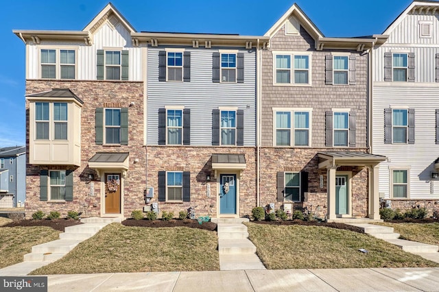 townhome / multi-family property featuring board and batten siding and a front yard