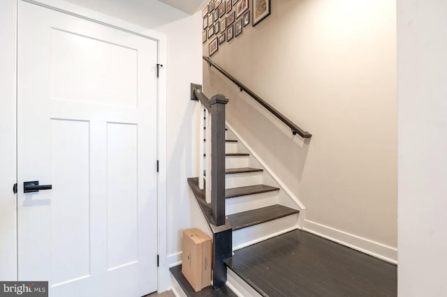 staircase featuring wood finished floors and baseboards