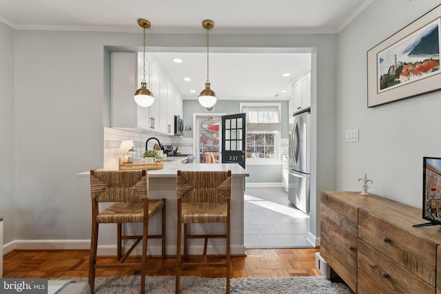 kitchen with stainless steel appliances, white cabinets, light countertops, decorative backsplash, and baseboards