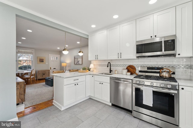 kitchen with a sink, white cabinetry, radiator, appliances with stainless steel finishes, and a peninsula