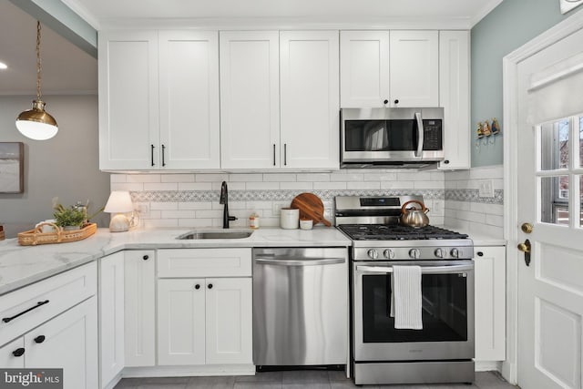 kitchen with white cabinets, light stone counters, appliances with stainless steel finishes, and a sink