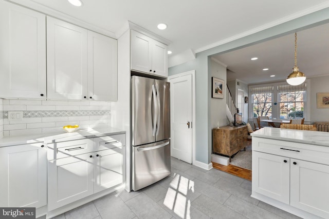 kitchen with ornamental molding, tasteful backsplash, freestanding refrigerator, white cabinets, and hanging light fixtures