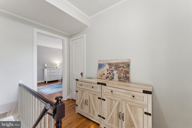 corridor with visible vents, an upstairs landing, light wood-style floors, and ornamental molding