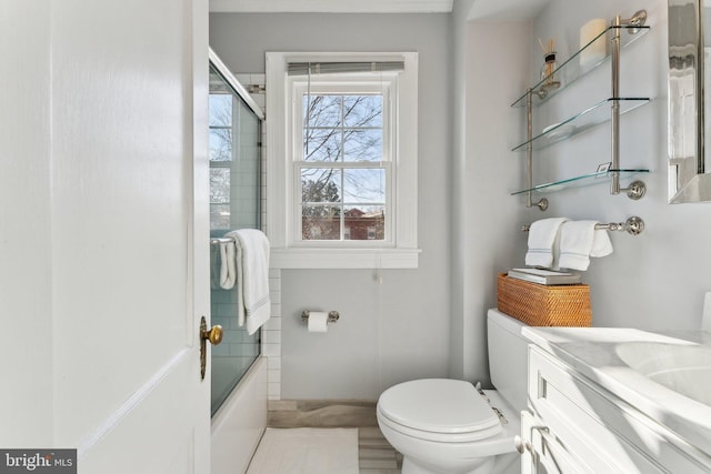 bathroom featuring combined bath / shower with glass door, toilet, and vanity