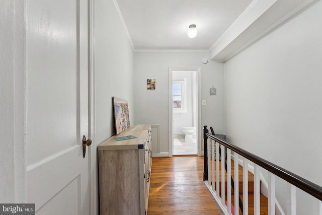 hall featuring crown molding, light wood-style flooring, and an upstairs landing