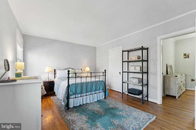 bedroom with baseboards, wood finished floors, and ornamental molding