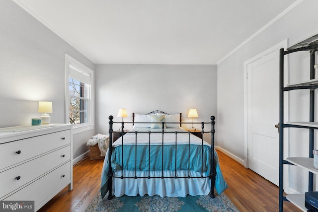 bedroom featuring baseboards, wood finished floors, and crown molding