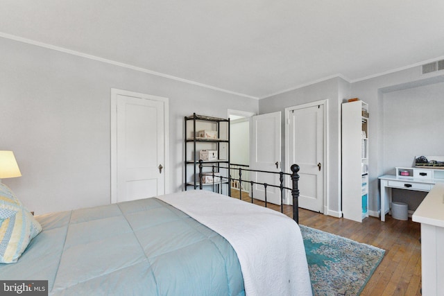 bedroom featuring visible vents, hardwood / wood-style floors, and ornamental molding