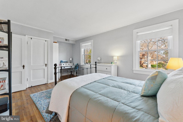 bedroom with visible vents, crown molding, and hardwood / wood-style floors