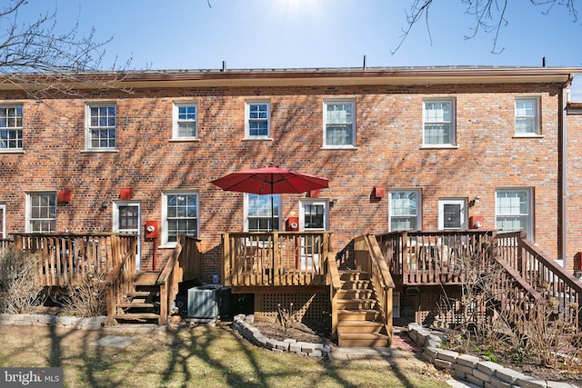 rear view of property with cooling unit, brick siding, a deck, and stairs