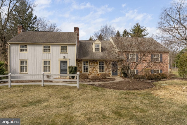 view of front of house with stone siding, a front lawn, a chimney, and fence