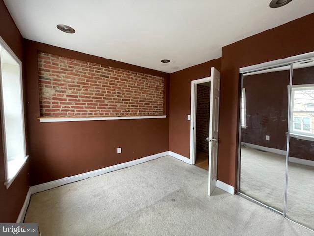 unfurnished bedroom with carpet, a closet, and baseboards