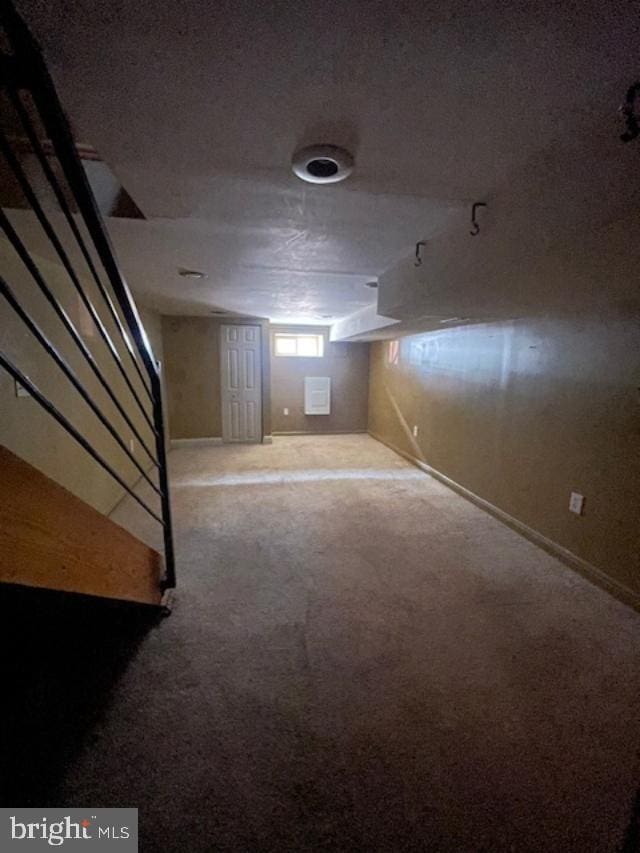 below grade area featuring stairway, carpet flooring, baseboards, and a textured ceiling