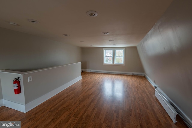 unfurnished room featuring baseboard heating, wood finished floors, and baseboards