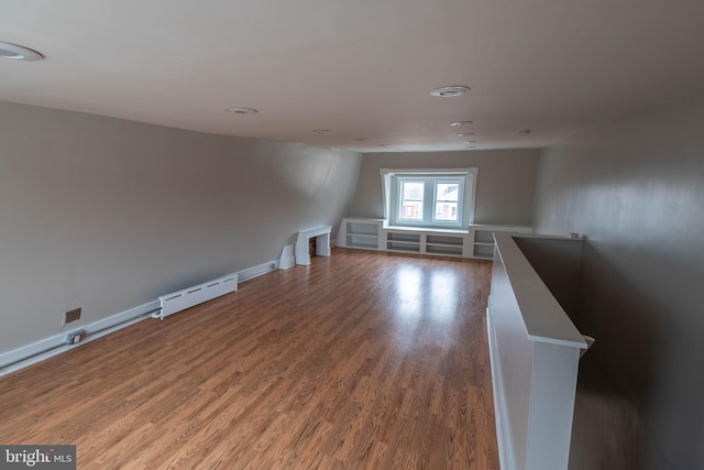 empty room featuring baseboard heating, baseboards, and wood finished floors