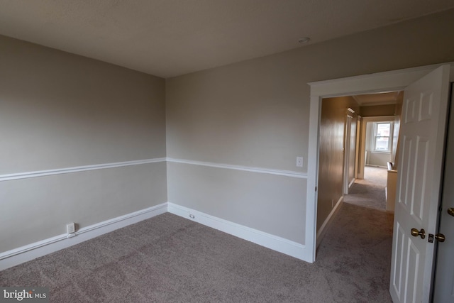 spare room featuring carpet floors and baseboards