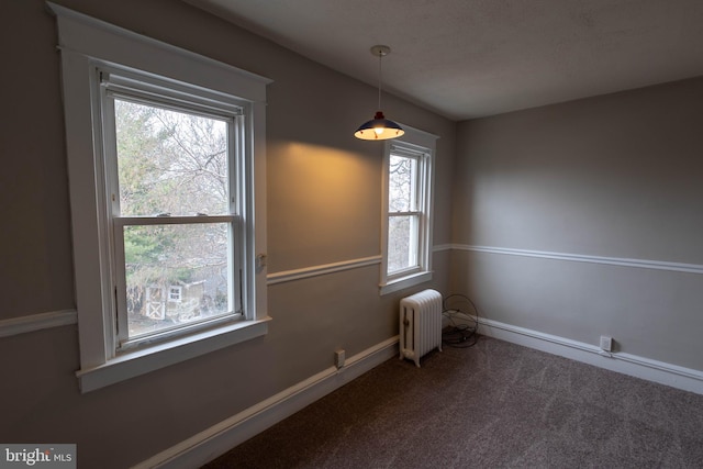 carpeted empty room featuring radiator and baseboards