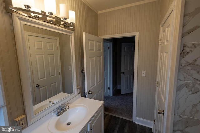 bathroom with ornamental molding, wood finished floors, vanity, and wallpapered walls