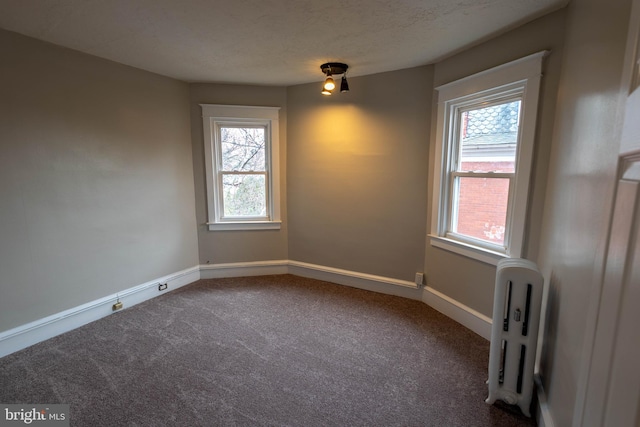 carpeted spare room with baseboards, a textured ceiling, and radiator