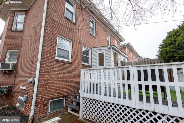 view of property exterior featuring brick siding, cooling unit, and a wooden deck