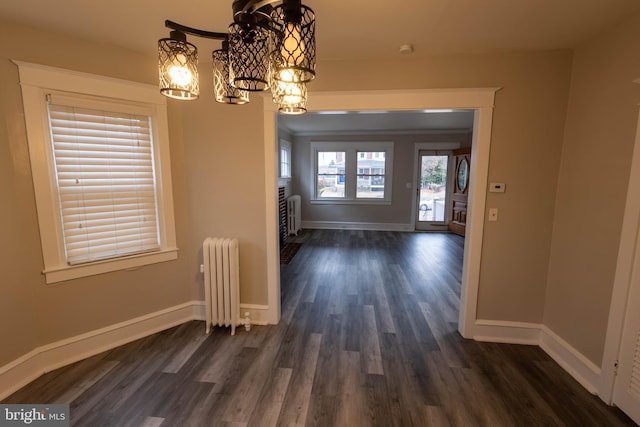 unfurnished dining area featuring an inviting chandelier, radiator heating unit, baseboards, and dark wood-type flooring