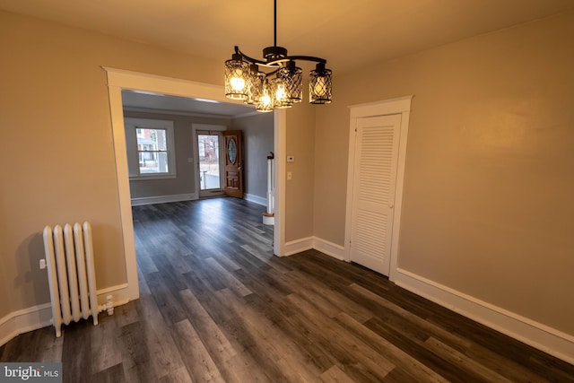 unfurnished dining area featuring a notable chandelier, radiator heating unit, baseboards, and dark wood-type flooring