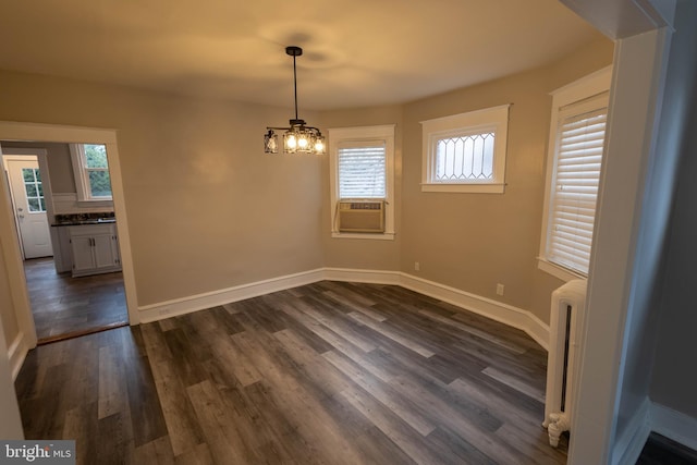 unfurnished dining area with baseboards, an inviting chandelier, dark wood finished floors, and radiator