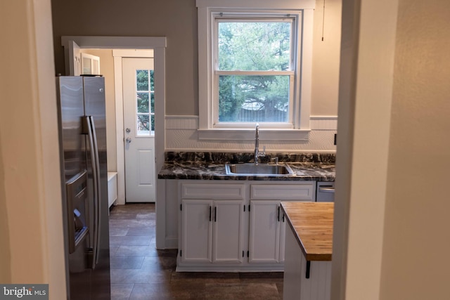 kitchen featuring stainless steel fridge, decorative backsplash, white cabinets, butcher block countertops, and a sink