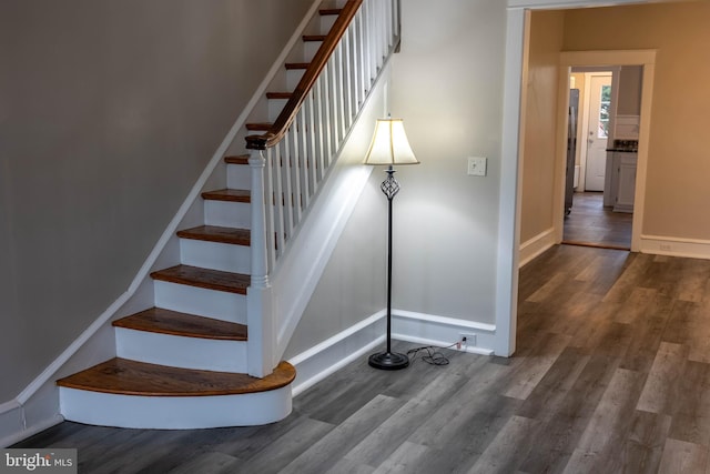 staircase featuring wood finished floors and baseboards