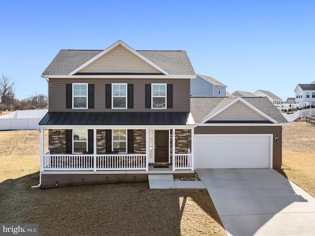 view of front of house with covered porch, concrete driveway, a standing seam roof, a garage, and stone siding