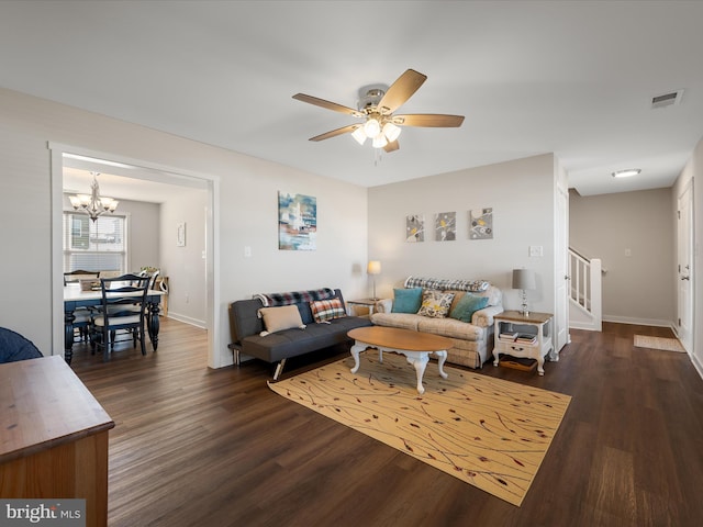 living room with visible vents, baseboards, dark wood-style floors, stairway, and ceiling fan with notable chandelier