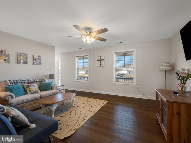 living room featuring ceiling fan, baseboards, visible vents, and dark wood finished floors