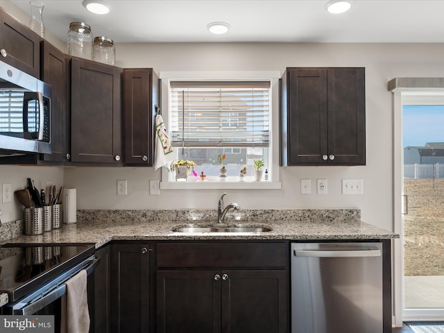 kitchen with appliances with stainless steel finishes, a wealth of natural light, a sink, and dark brown cabinetry