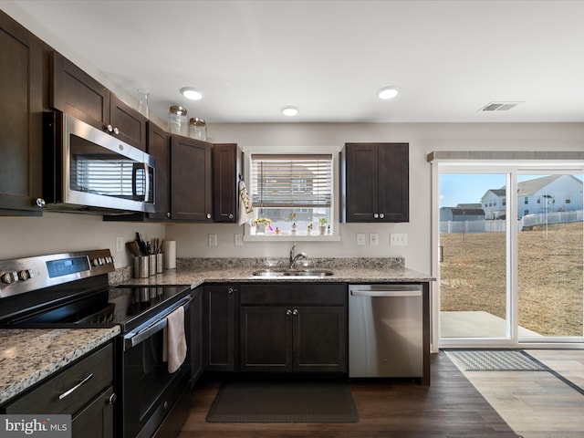 kitchen with dark brown cabinetry, visible vents, appliances with stainless steel finishes, dark wood-style flooring, and a sink