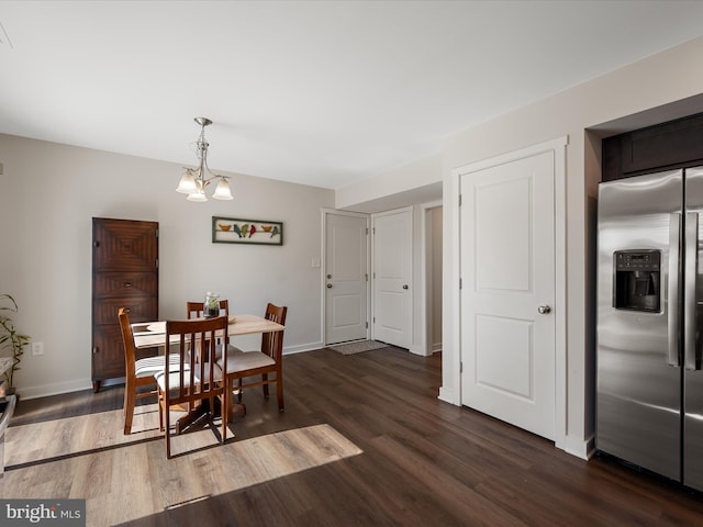 dining area with dark wood finished floors, a notable chandelier, and baseboards