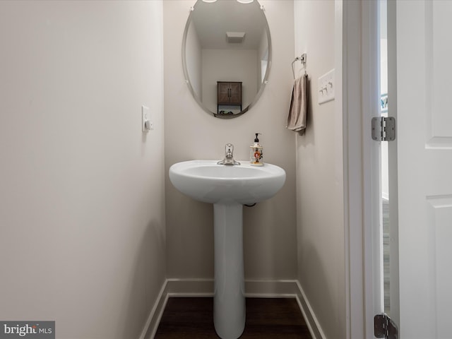 bathroom featuring a sink, visible vents, baseboards, and wood finished floors