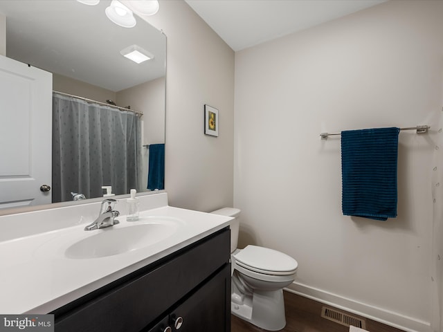 full bathroom featuring visible vents, toilet, vanity, wood finished floors, and baseboards