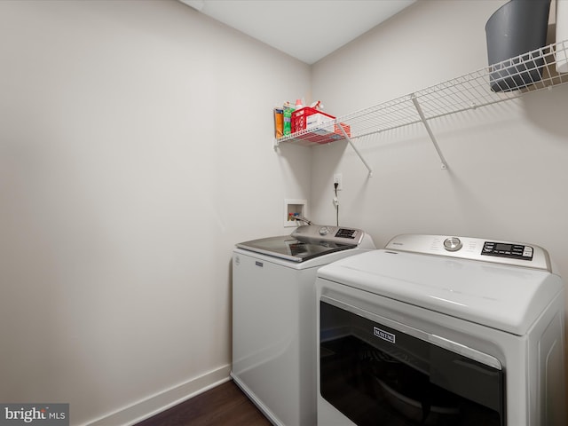 clothes washing area with laundry area, washer and clothes dryer, dark wood finished floors, and baseboards