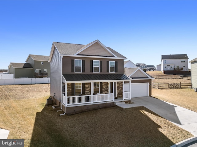 view of front of home featuring a porch, a standing seam roof, driveway, and fence