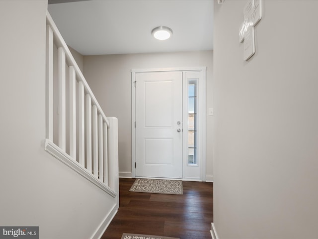 foyer entrance featuring dark wood-style floors, stairway, and baseboards