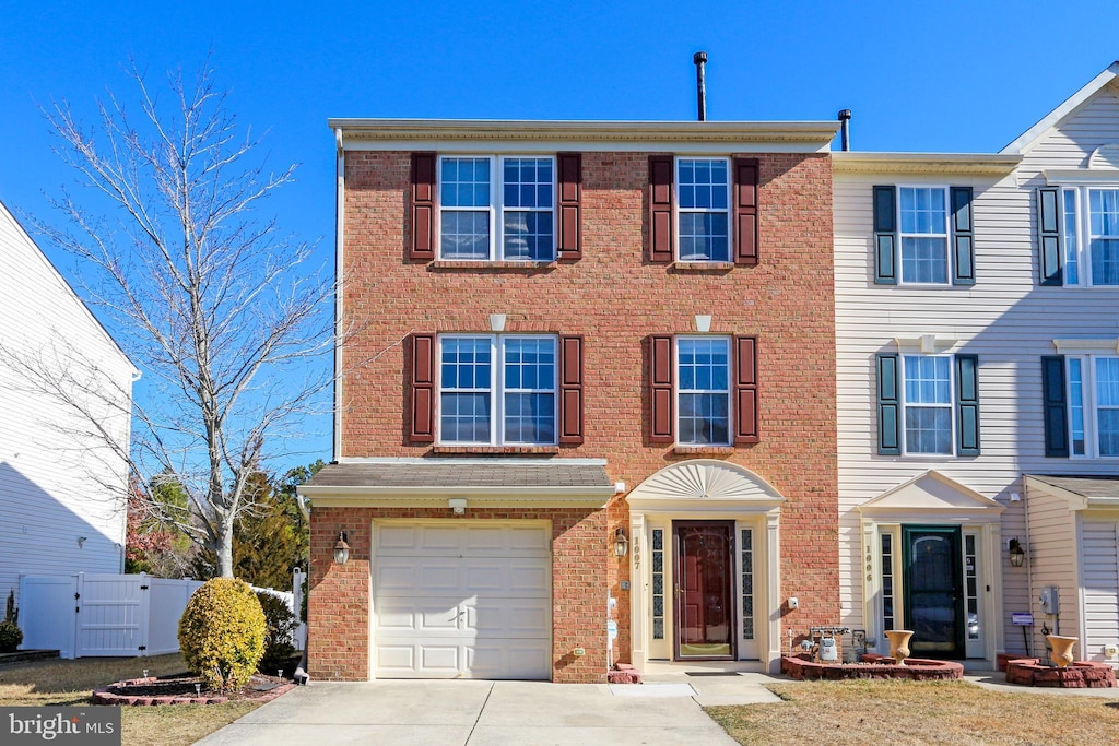 multi unit property with brick siding, concrete driveway, an attached garage, a gate, and fence