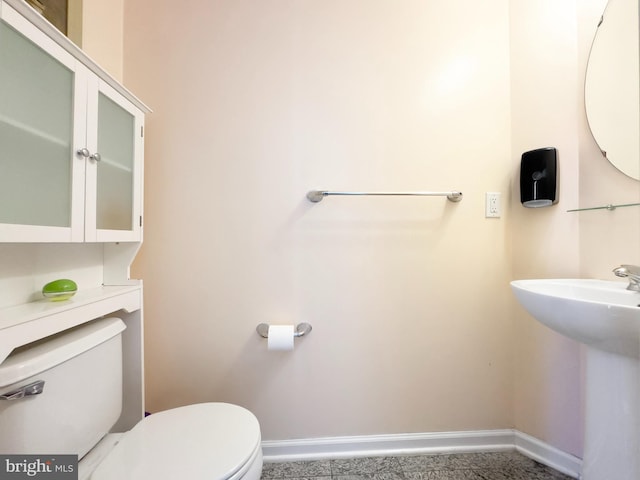 half bathroom with toilet, baseboards, and a sink