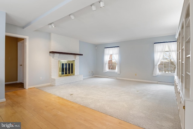 unfurnished living room with a baseboard heating unit, a fireplace, wood finished floors, and baseboards