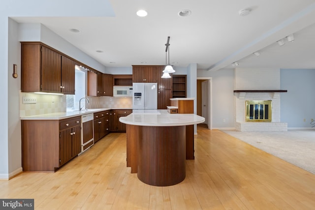 kitchen with white appliances, tasteful backsplash, a kitchen island, and light countertops