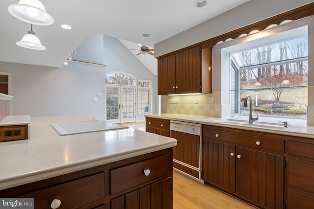 kitchen featuring light countertops, backsplash, a sink, stovetop, and dishwasher