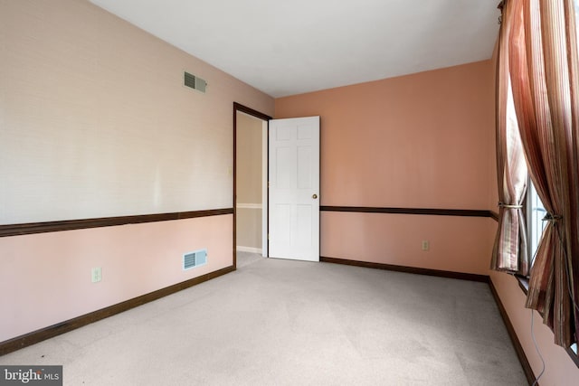 unfurnished room featuring baseboards, visible vents, and carpet flooring